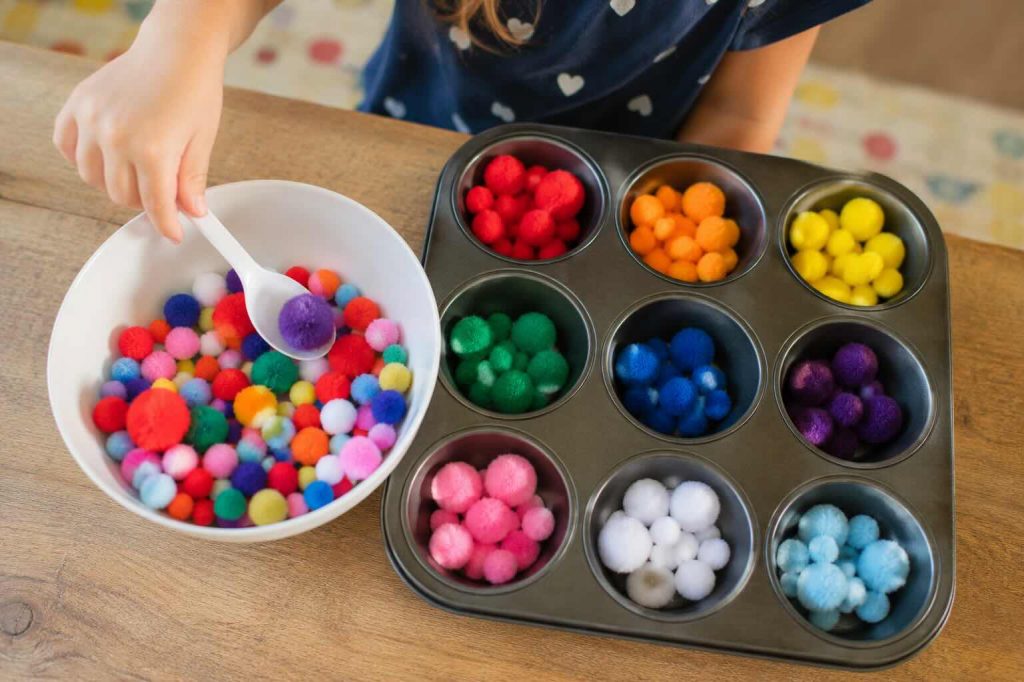 various pom poms being organized by a child